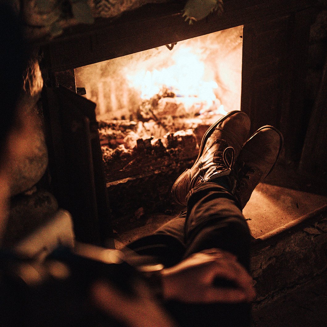 man with boots propped up in front of a fireplace